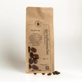 140 g Kaffeepackung aus braunem Kraftpapier mit Kaffeebohnen im Vordergrund von Der Kaffeemacher.
140 g coffee package made of brown kraft paper wirh Coffeebeans from Der Kaffeemacher.
